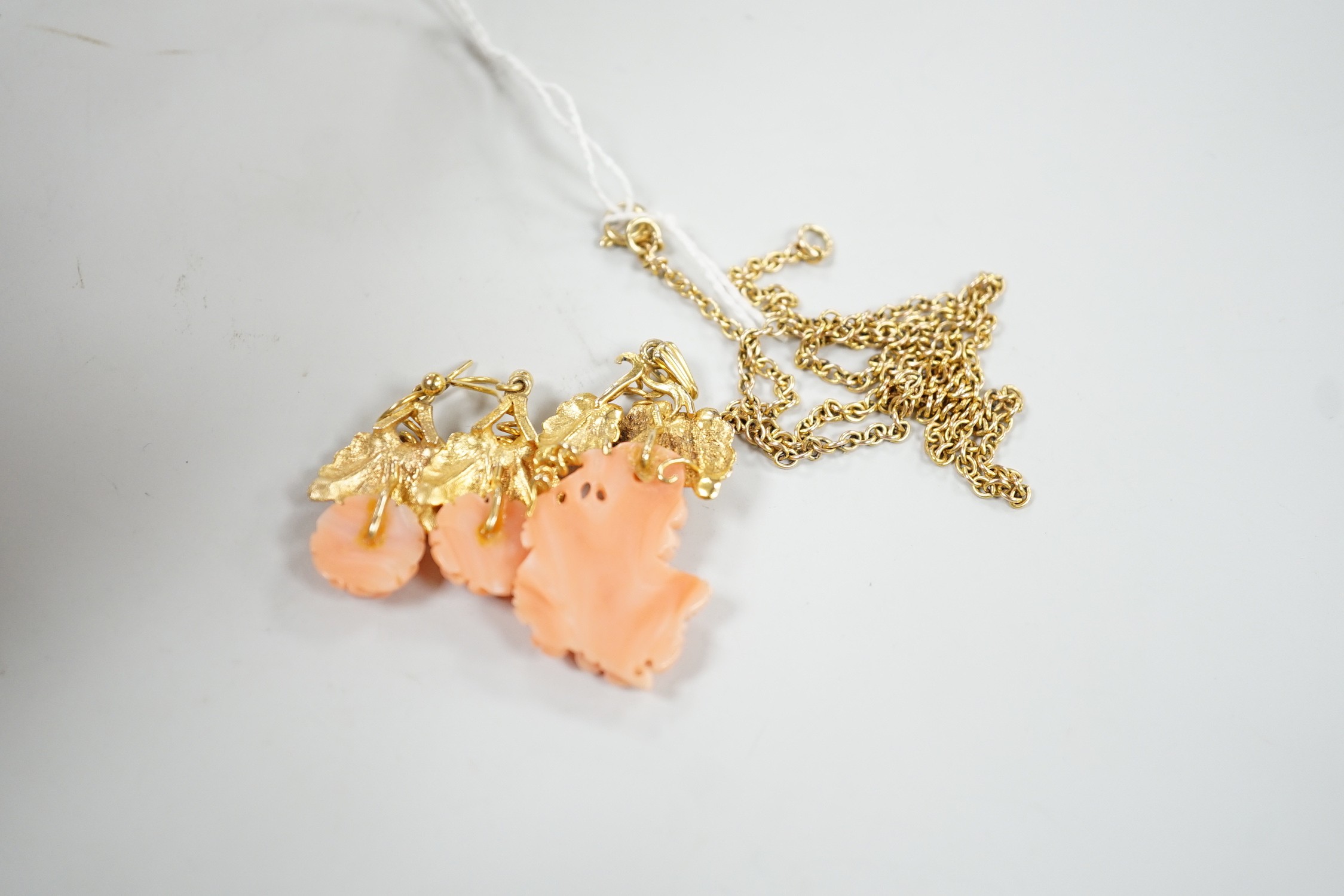 A modern suite of yellow metal and carved coral jewellery, comprising a pendant , 40mm, on chain, 45cm and a pair of matching drop earrings stamped 9ct gold, 26mm, gross 15.2 grams.